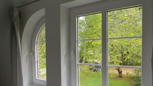 A room with a large window overlooking a garden. - Vacation apartment Odde (Nebel)