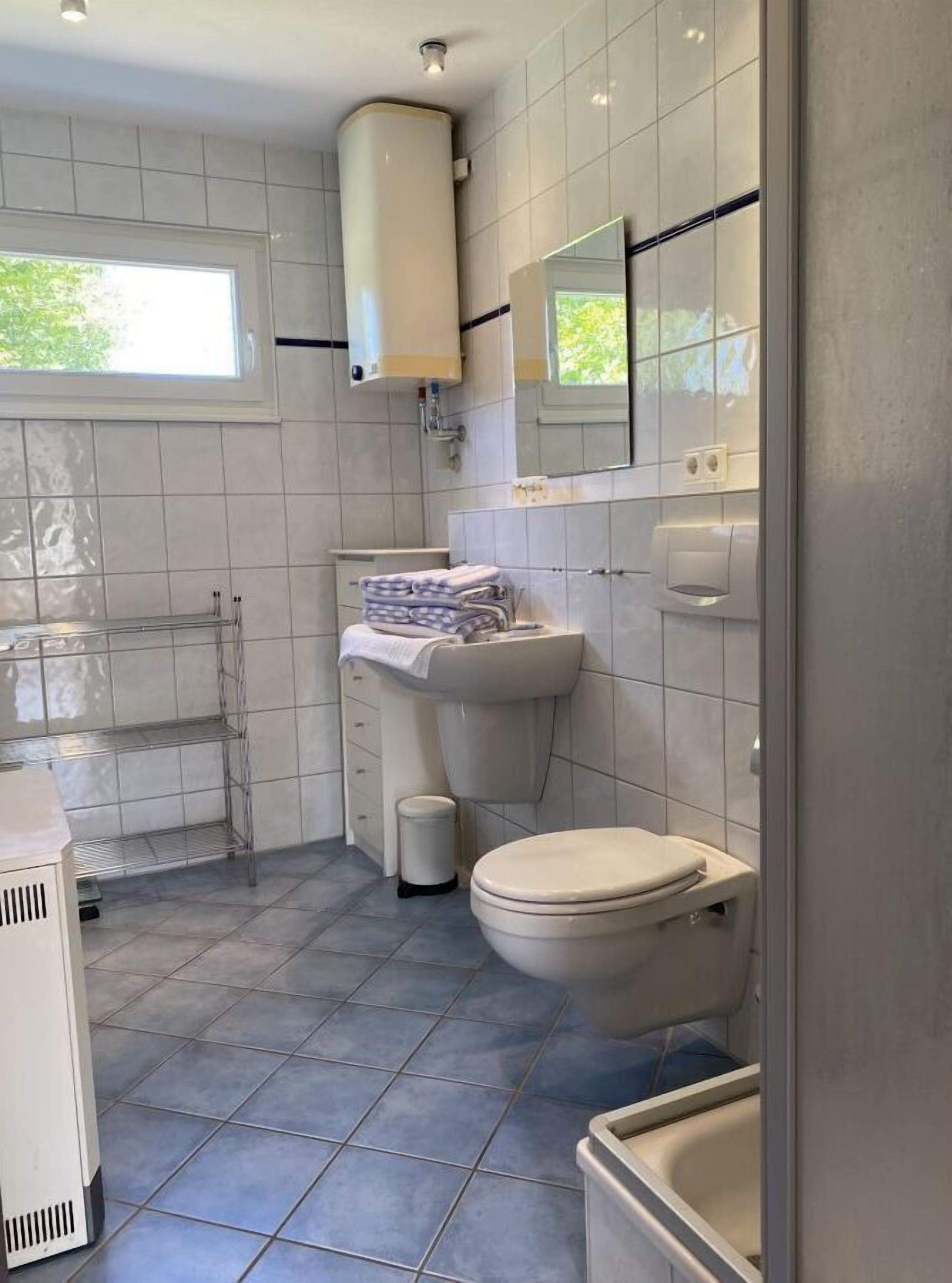 Et moderne badeværelse med toilet, vask og håndklædestang.