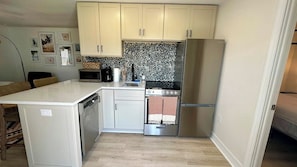 A compact kitchen with a refrigerator, stove, microwave, and dishwasher.