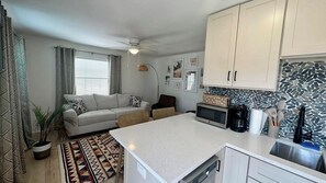 A compact living space with a kitchenette, a sofa, a dining area, and a ceiling fan.