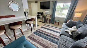 A living room with a sofa, a television, a coffee table, and a striped rug. - Turtle Nest 6 - Quick Walk to Beach (Fort Myers Beach)