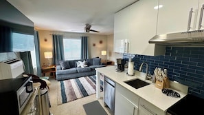 A compact living space with a kitchenette, a sofa, a dining table, and a ceiling fan.
