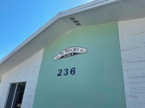 A building corner with a sign reading 'The Turtle Nest' and the number '236' on a green wall.