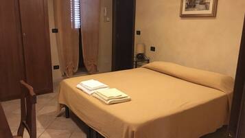 Una camera d'albergo con un letto, una sedia, una porta e un quadro appeso al muro.
