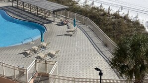 Poolområde ved stranden med havudsigt, træterrasse og liggestole.