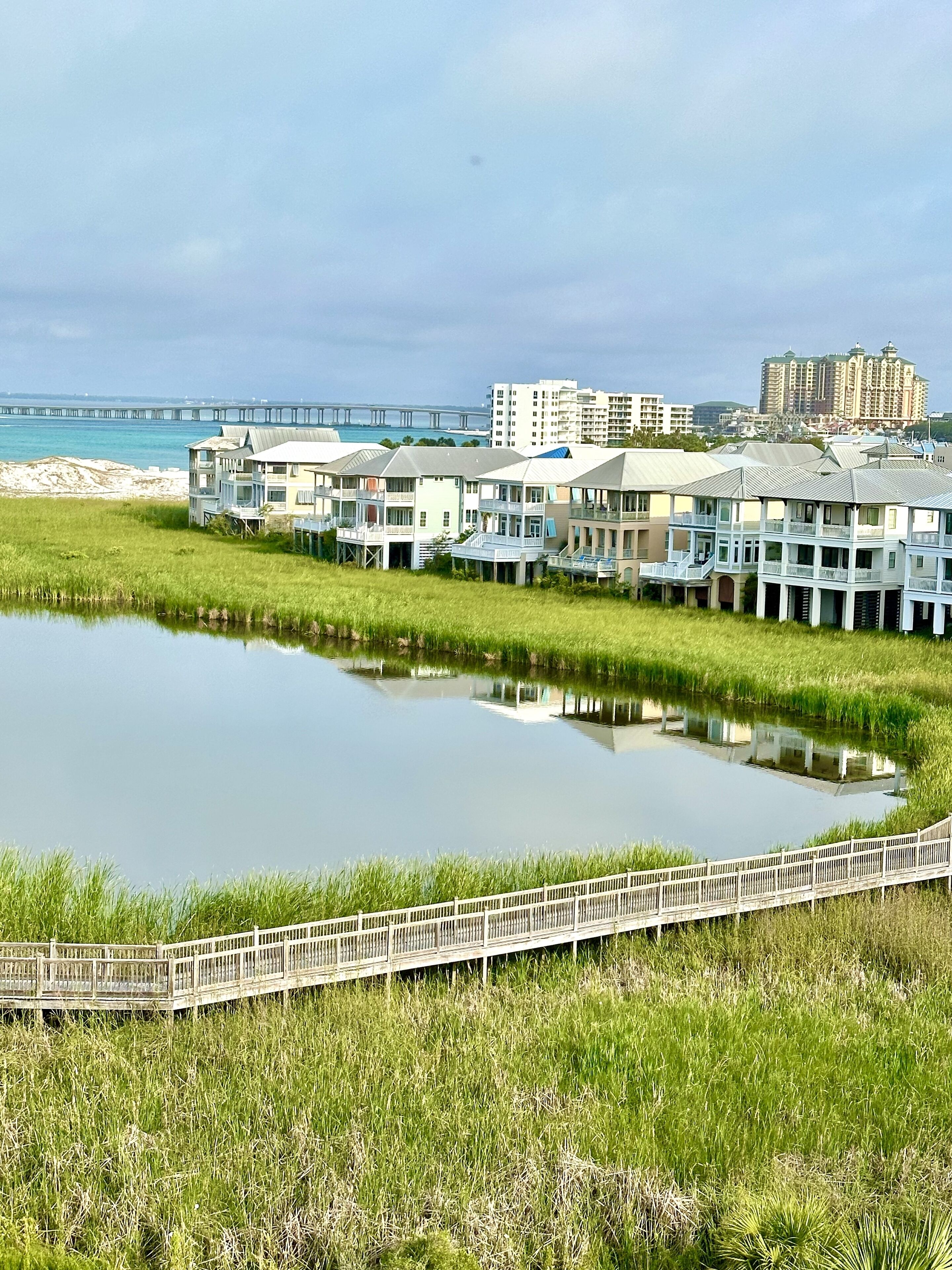 A waterfront property with a pond, a wooden boardwalk, and buildings with balconies overlooking the water.