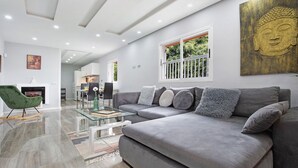 Ein modernes Wohnzimmer mit einem grauen Sofa, einem Glastisch und einem grünen Sessel.