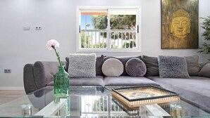 Ein modernes Wohnzimmer mit einem Glastisch, einem grauen Sofa und einem Buddha-Gemälde.