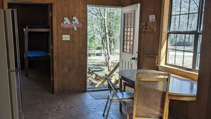 A wooden cabin with a dining table, chairs, and a bench. There is a door leading outside, a window, and a ceiling fan. -  Come enjoy the Ocoee River and all its beautiful nature with us! (Benton)