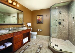 Bathroom features a sink, toilet, shower, and mirror above a vanity with storage.