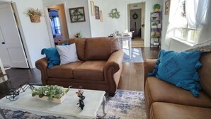 A living room with a brown sofa, a coffee table with decorative items, and a blue patterned rug. - Comfy 2 bedroom home, near Palo Duro Canyon! (Canyon)