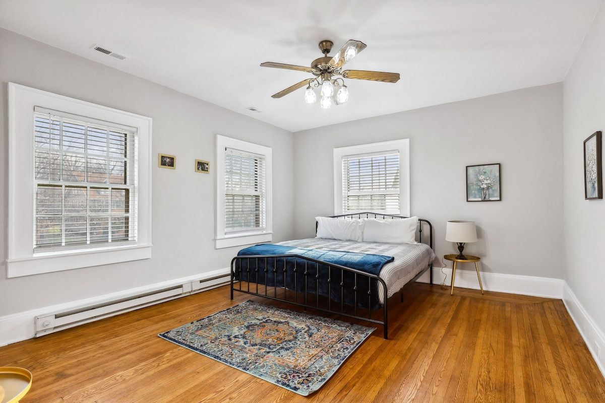 Quarto com cama, ventilador de teto e janela com persianas.