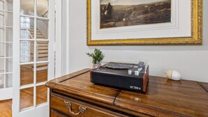 A room with a wooden desk, a vinyl record player, a framed landscape painting, and a staircase leading to an upper floor. - Wade Manor: Game-room, Gym, Office and Fenced in Backyard (Cleveland)