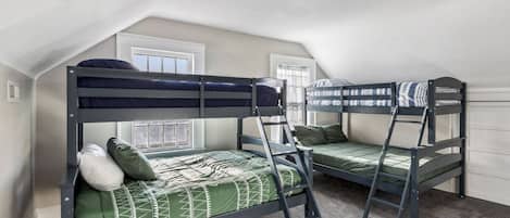 Una habitación con dos literas, una escalera y un ventanal.