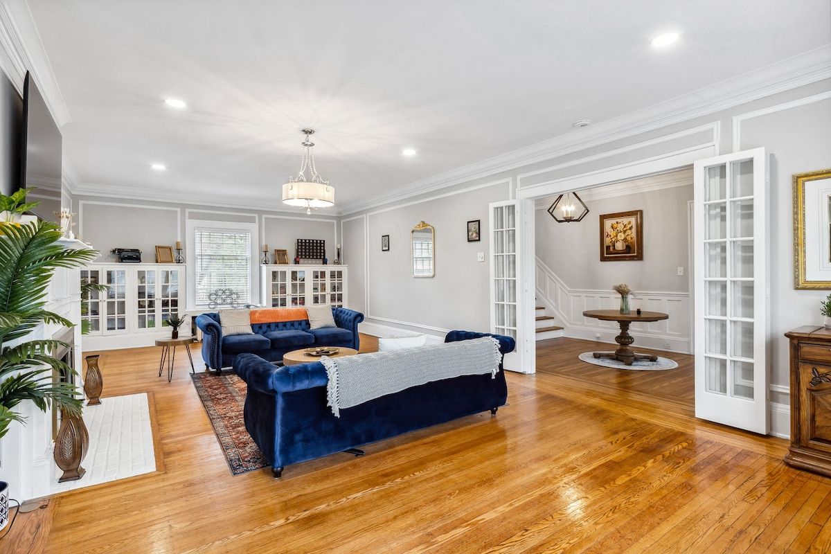 A spacious living room with a blue sofa set, a wooden coffee table, and a chandelier.