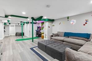 Un salón moderno con sofá, reposapiés y detalles estructurales verdes.