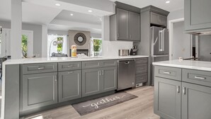 A modern kitchen with grey cabinetry, stainless steel appliances, and a central island.
