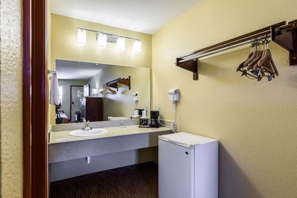 A hotel bathroom with a sink, mirror, towel rack, and a small white cabinet.