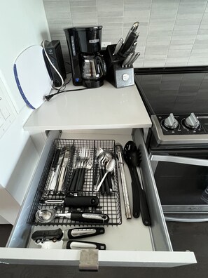 Una cucina con una macchina da caffè, un set di coltelli e utensili in un cassetto.