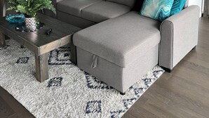 A modern living room with a grey sectional sofa, a coffee table, and a patterned rug.