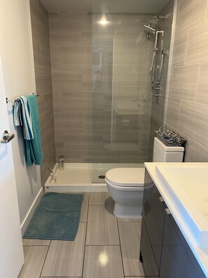 Un bagno moderno con doccia a vetro, un water e una vasca da bagno.