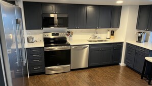 A modern kitchen with dark cabinets, stainless steel appliances, and a wooden floor. - OCEANFRONT with Balcony, Updated Condo; Gorgeous views; sleeps 6 (Ocean City)