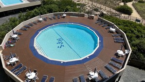 A circular pool with 'HPS' written on the water, surrounded by sun loungers and tables on a wooden deck. - OCEANFRONT with Balcony, Updated Condo; Gorgeous views; sleeps 6 (Ocean City)
