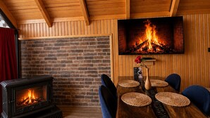 Una habitación acogedora con chimenea de ladrillo, techo de madera y comedor con sillas y mesa.