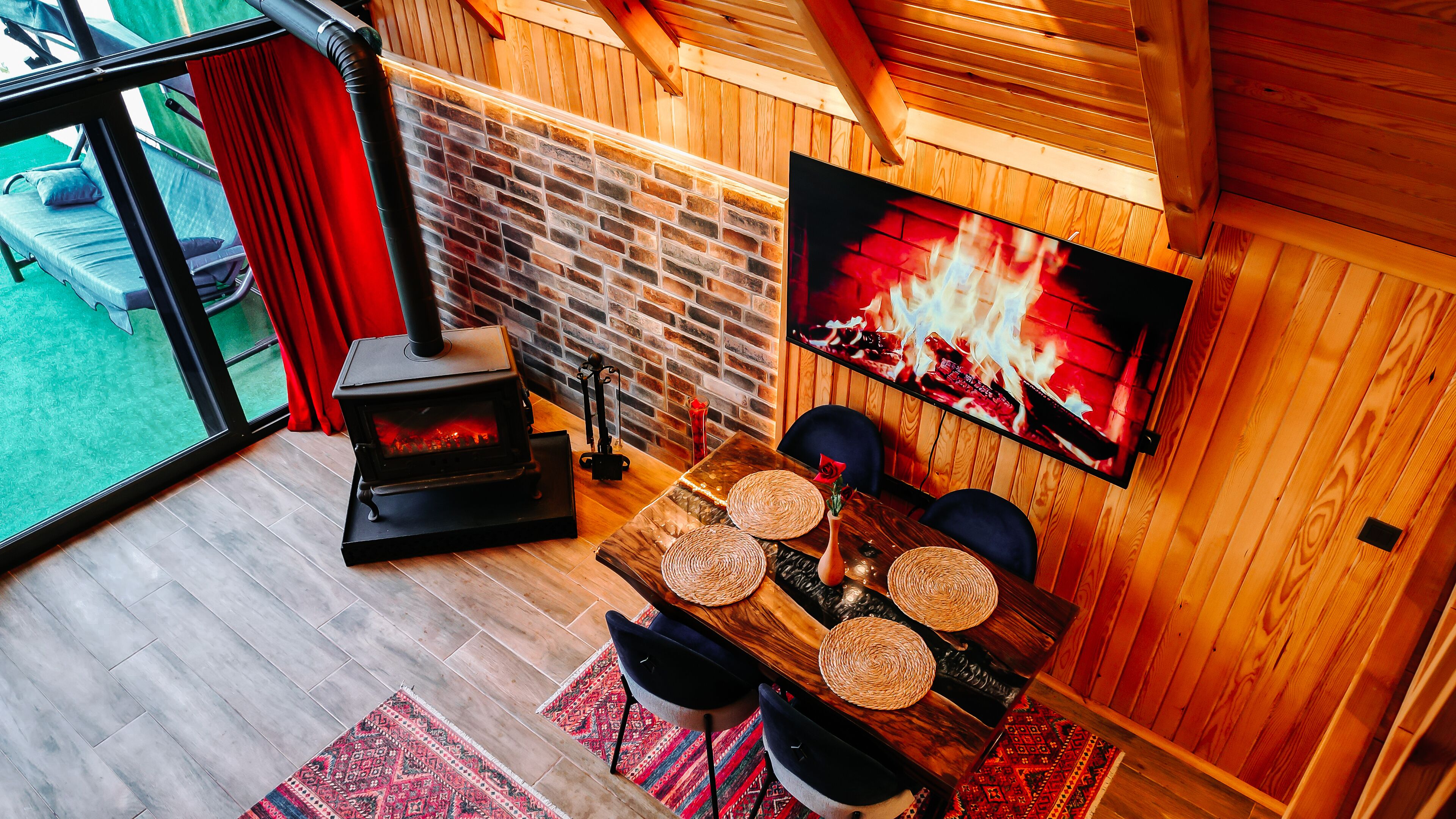A cozy room with a fireplace, a dining table with woven placemats, and a TV displaying a fire scene.