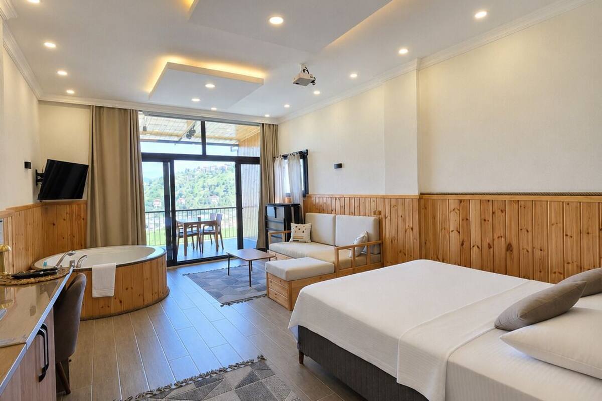 Een moderne hotelkamer met een groot bed, een slaapbank, een bureau en een bad.