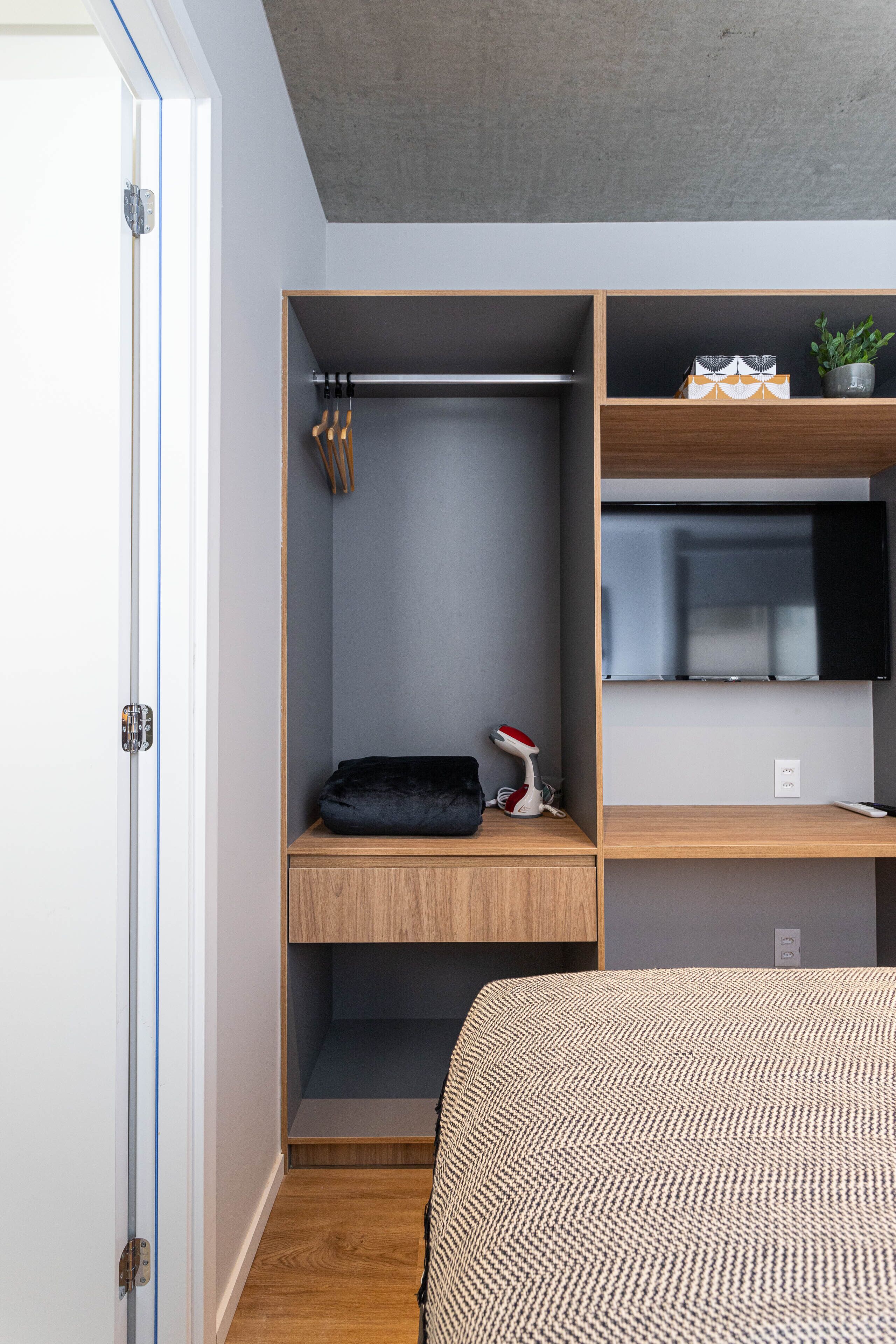 A bedroom with a bed, a wardrobe, and a desk area.
