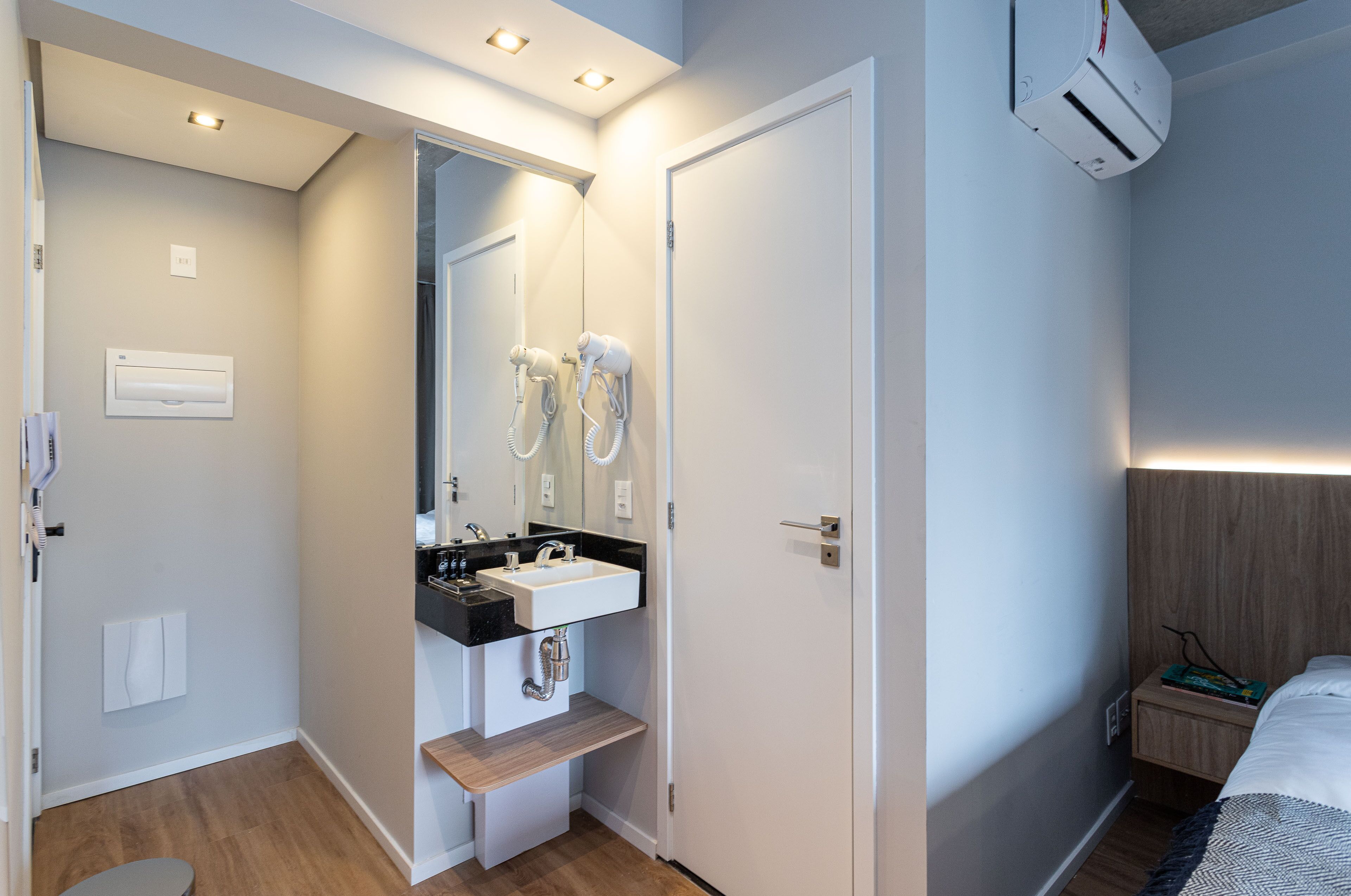 A modern bathroom with a sink, mirror, and two hair dryers.