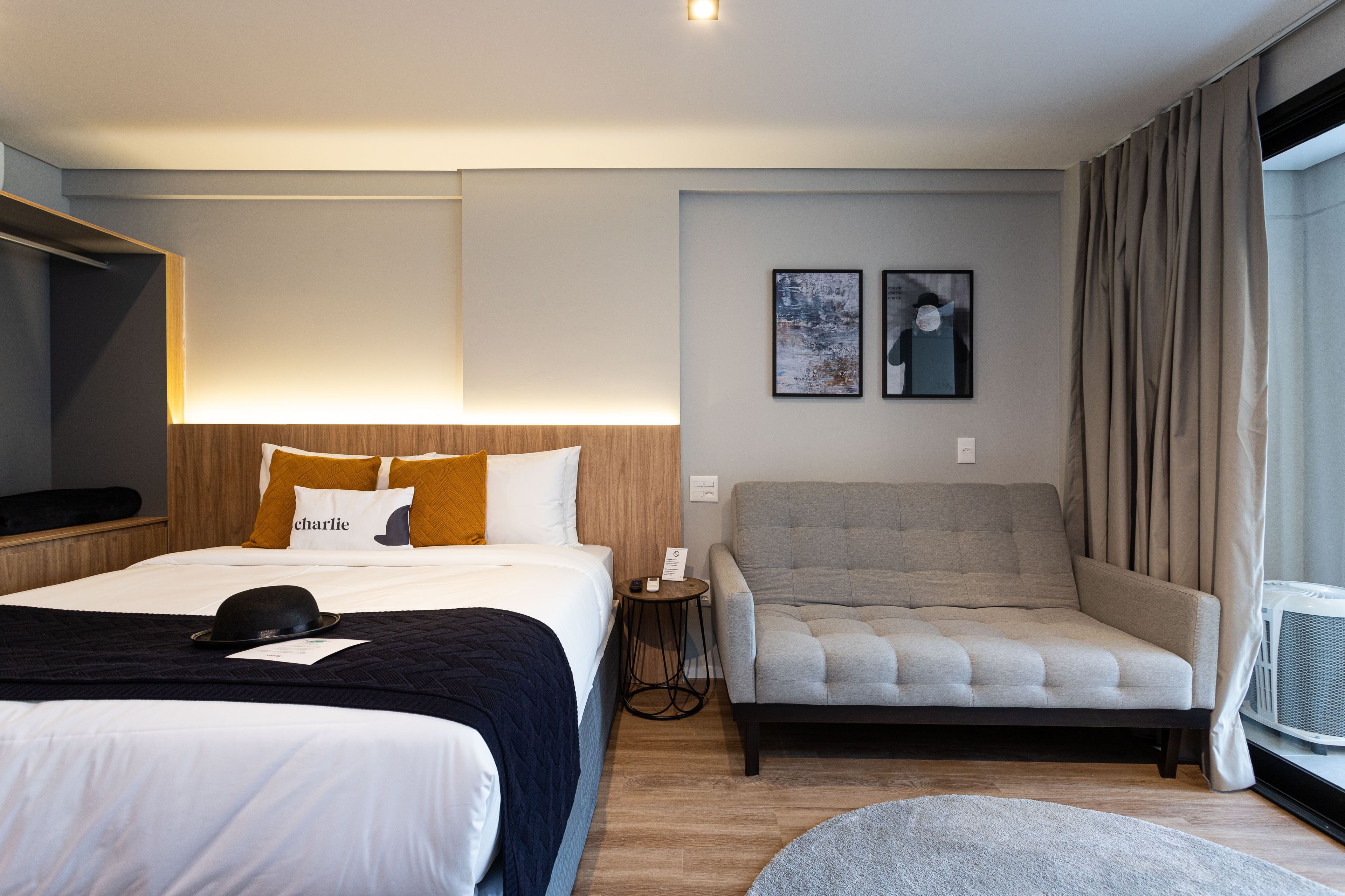 Ein Hotelzimmer mit zwei Betten, einem Sofa, einem kleinen Tisch und einem Fenster mit Vorhängen.