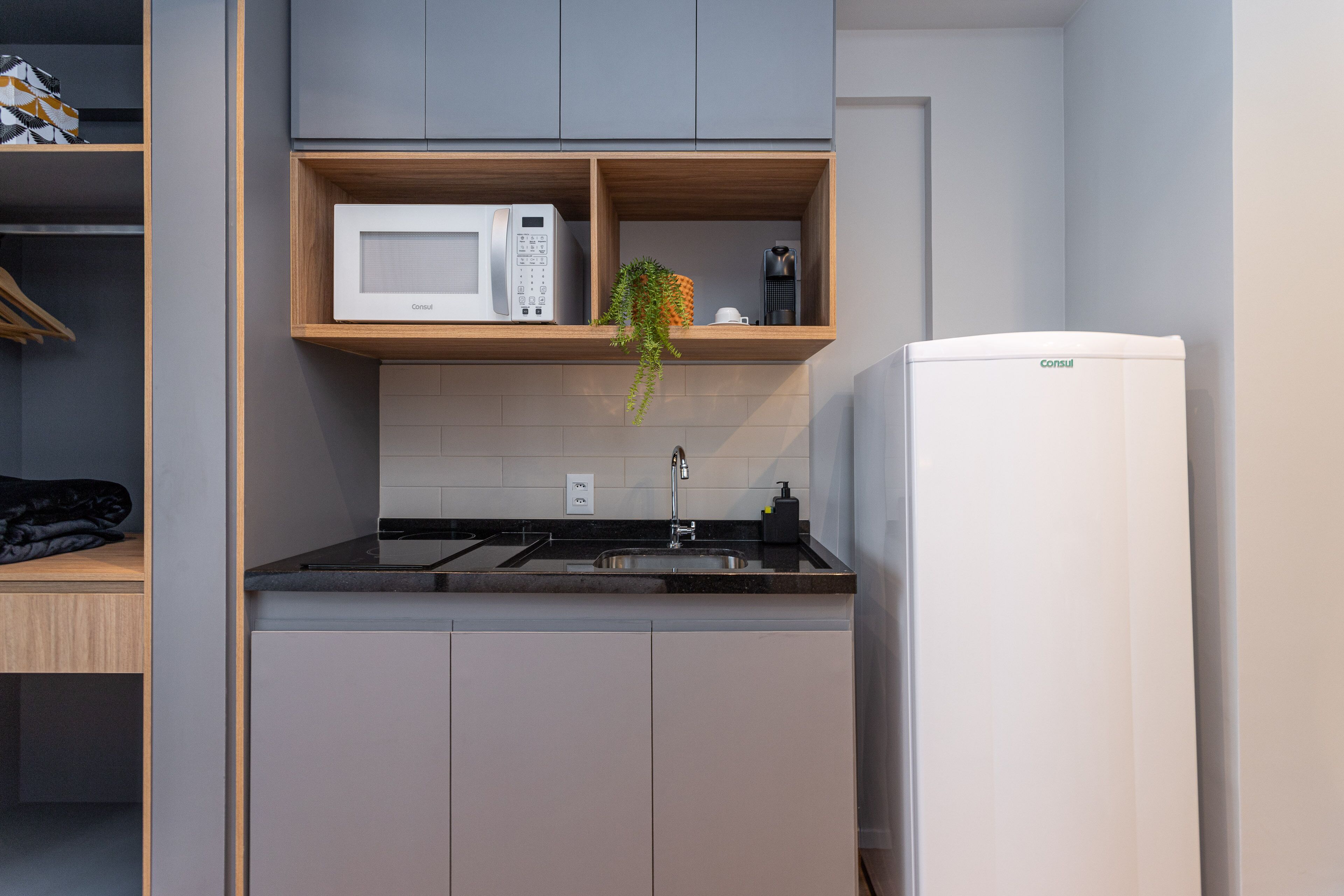 A compact kitchen with a microwave, coffee maker, and a refrigerator.
