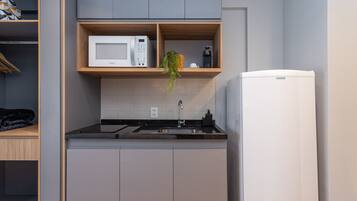 A compact kitchen with a microwave, coffee maker, and a refrigerator.