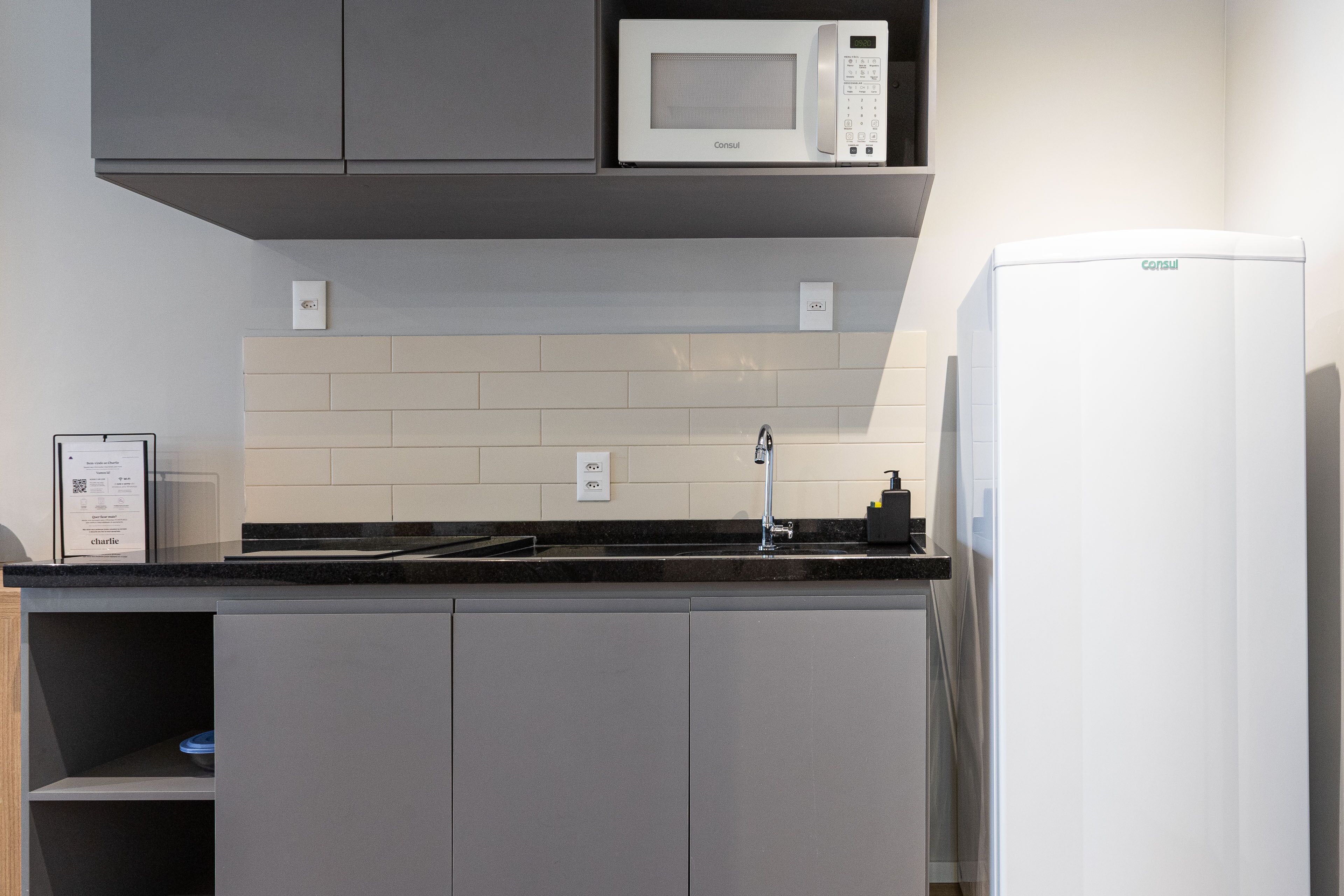 Una cucina moderna con mobili grigi, un forno a microonde bianco e un frigorifero integrato.