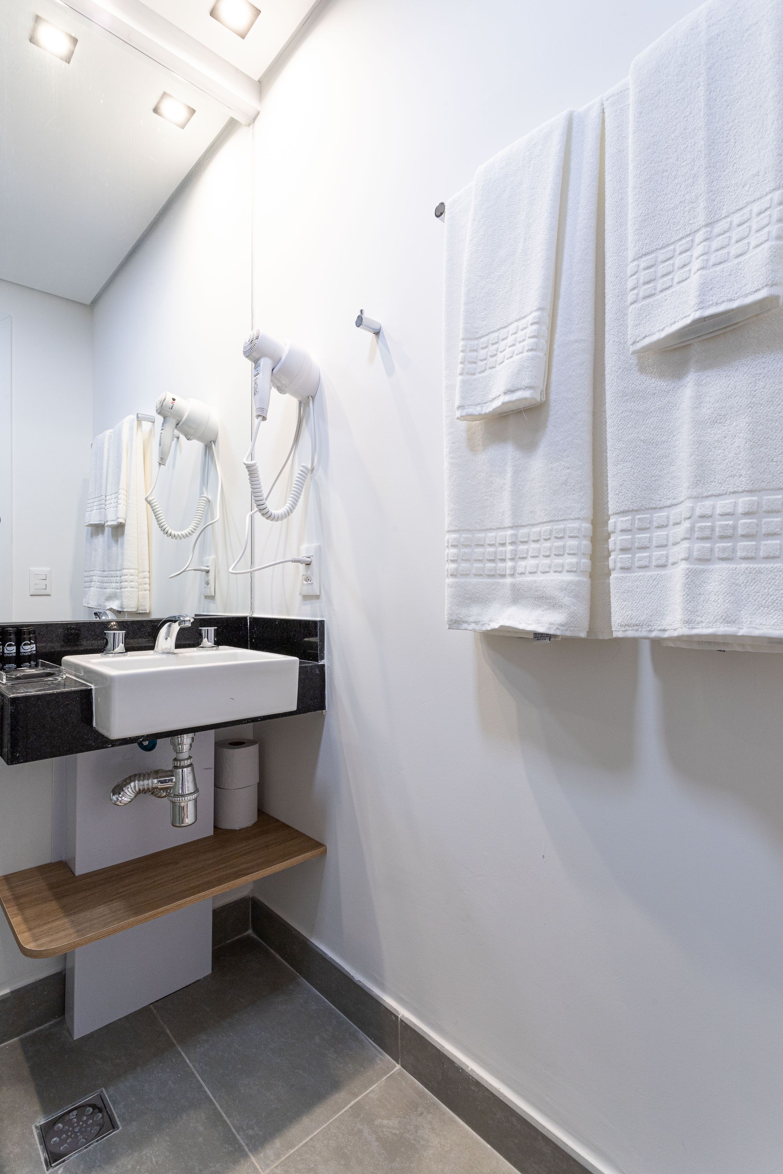 A modern bathroom with a white sink, towel rack, and hairdryer.