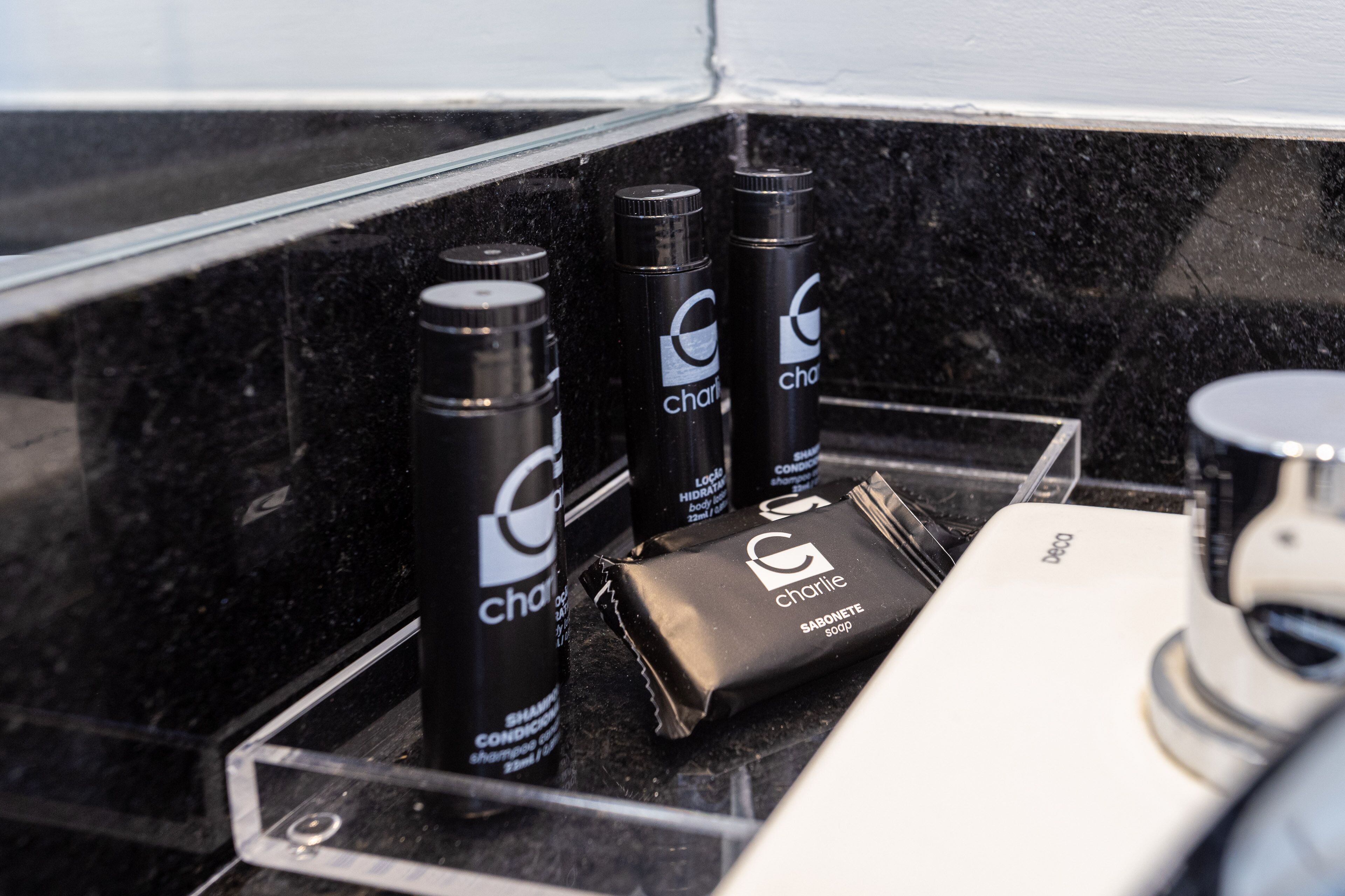 Un ripiano del bagno con articoli da toilette, tra cui bottiglie di shampoo, balsamo e sapone.