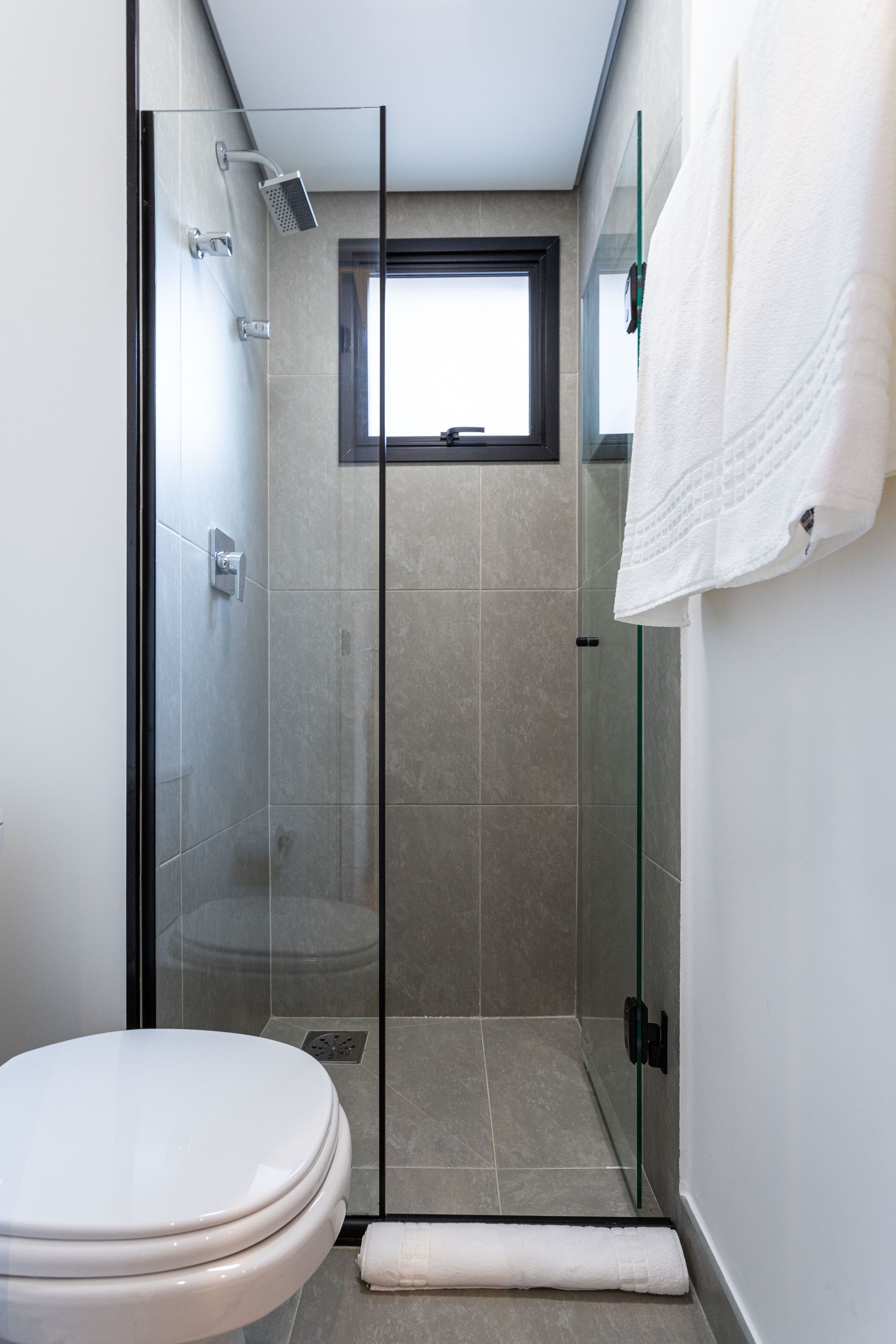 Ein modernes Badezimmer mit einer Glasdusche, einer Toilette und einem Handtuchhalter.