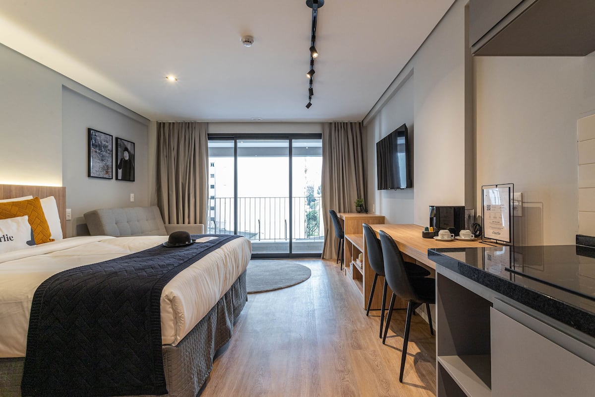 Ein modernes Hotelzimmer mit Bett, Schreibtisch und einer Küchenzeile.