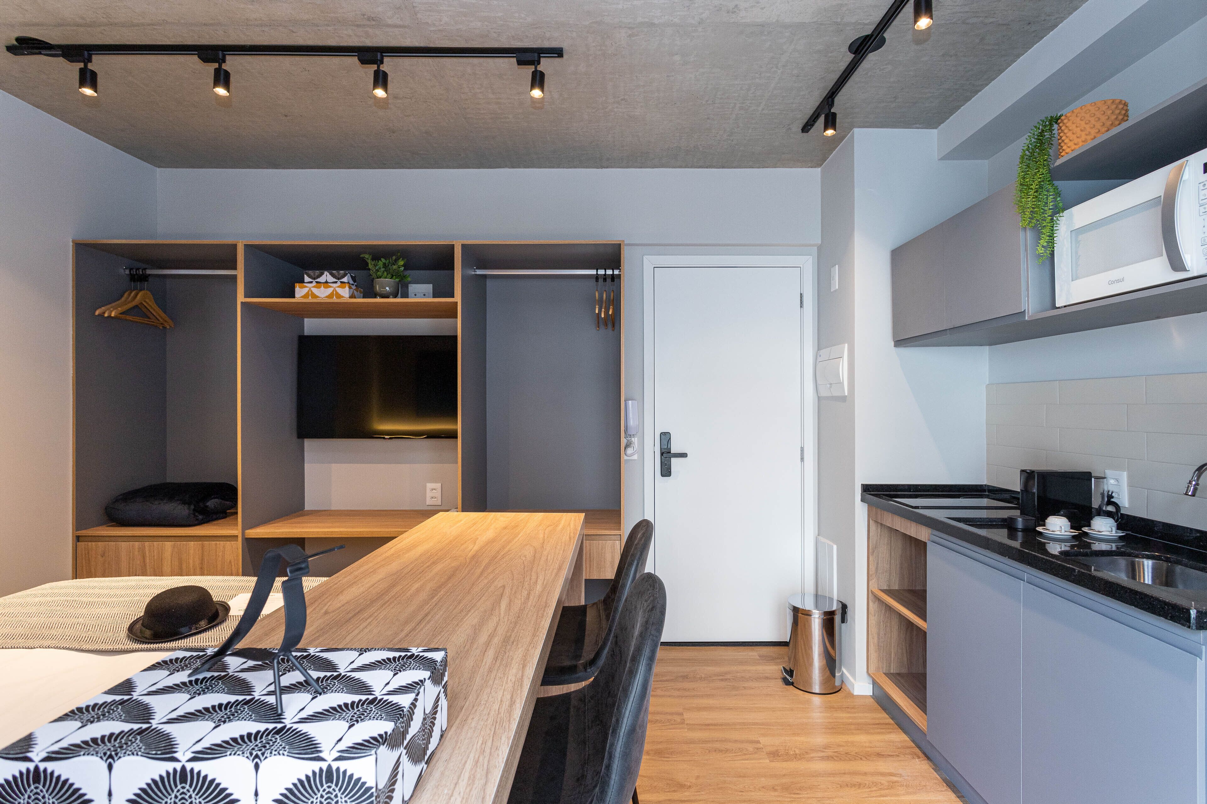 A modern kitchen with a built-in microwave, a sink, and a countertop. There is a dining area with a wooden table and chairs.
