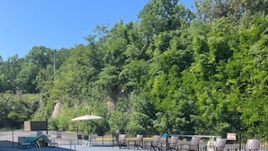 Une piscine avec des chaises longues et une clôture, entourée d’arbres.