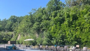 A swimming pool with lounge chairs and a fence, surrounded by trees. - Private Studio at Oak Ridge in Branson with Pool (Branson)