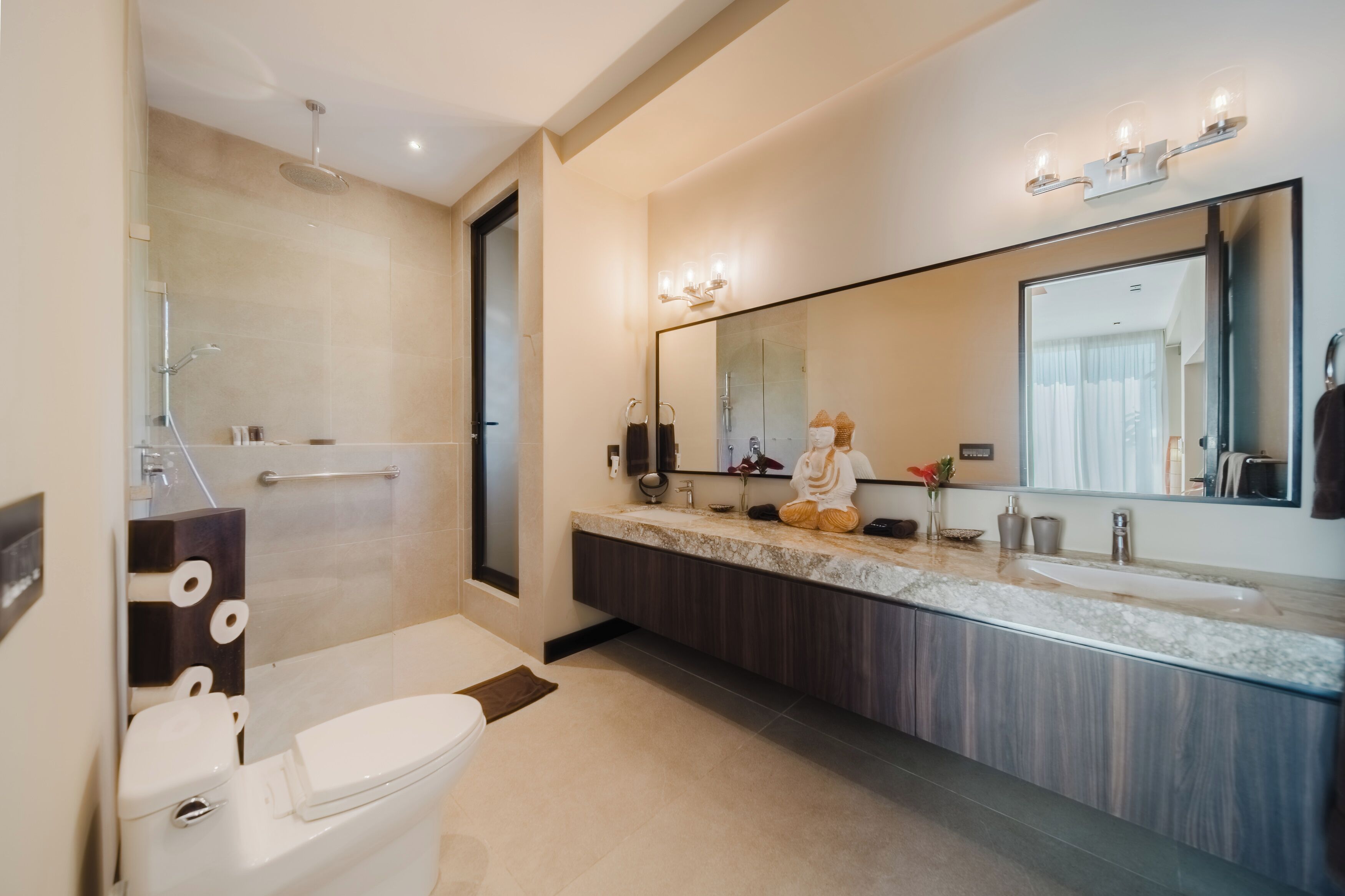 Een moderne badkamer met toilet, bidet, wastafel met grote spiegel en douchegedeelte.
