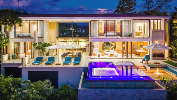 A modern two-story house with a swimming pool, outdoor seating, and a staircase leading to the upper level.