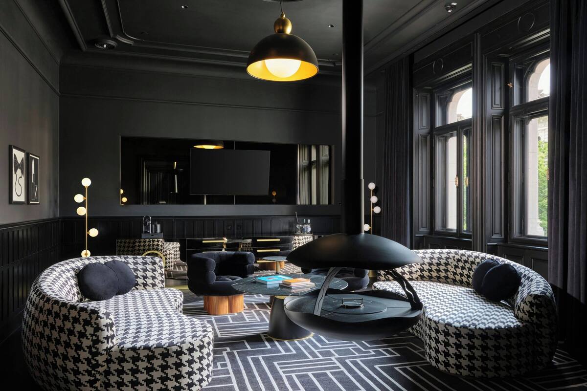 A modern living room with houndstooth patterned sofas, a round coffee table, and a large flat-screen TV.