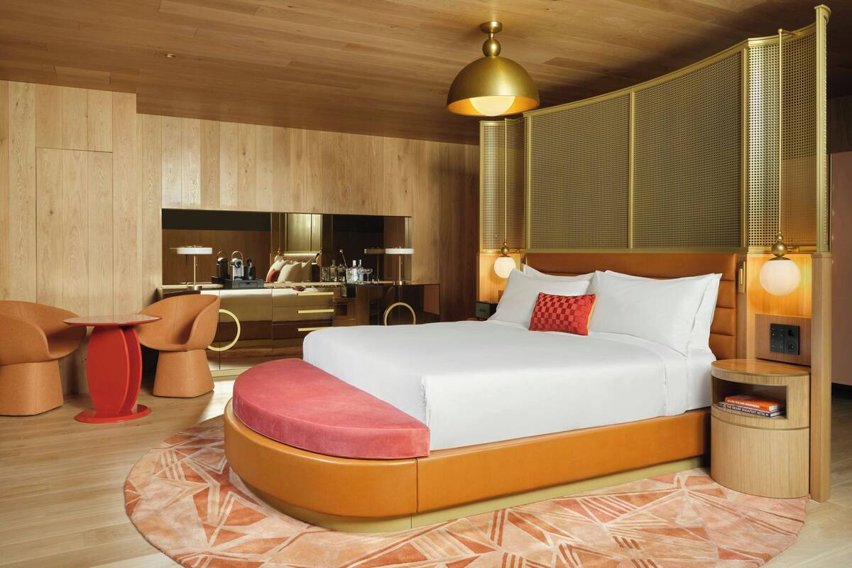 A modern hotel room with a large bed, a desk, and a seating area.