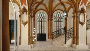 A grand staircase with ornate railings, a chandelier, and stained glass windows. - W Budapest (Budapest)