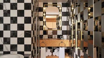 Un bagno moderno con parete rivestita in piastrelle bianche e nere a scacchi, uno specchio con cornice dorata e un lavabo con piano in sughero.