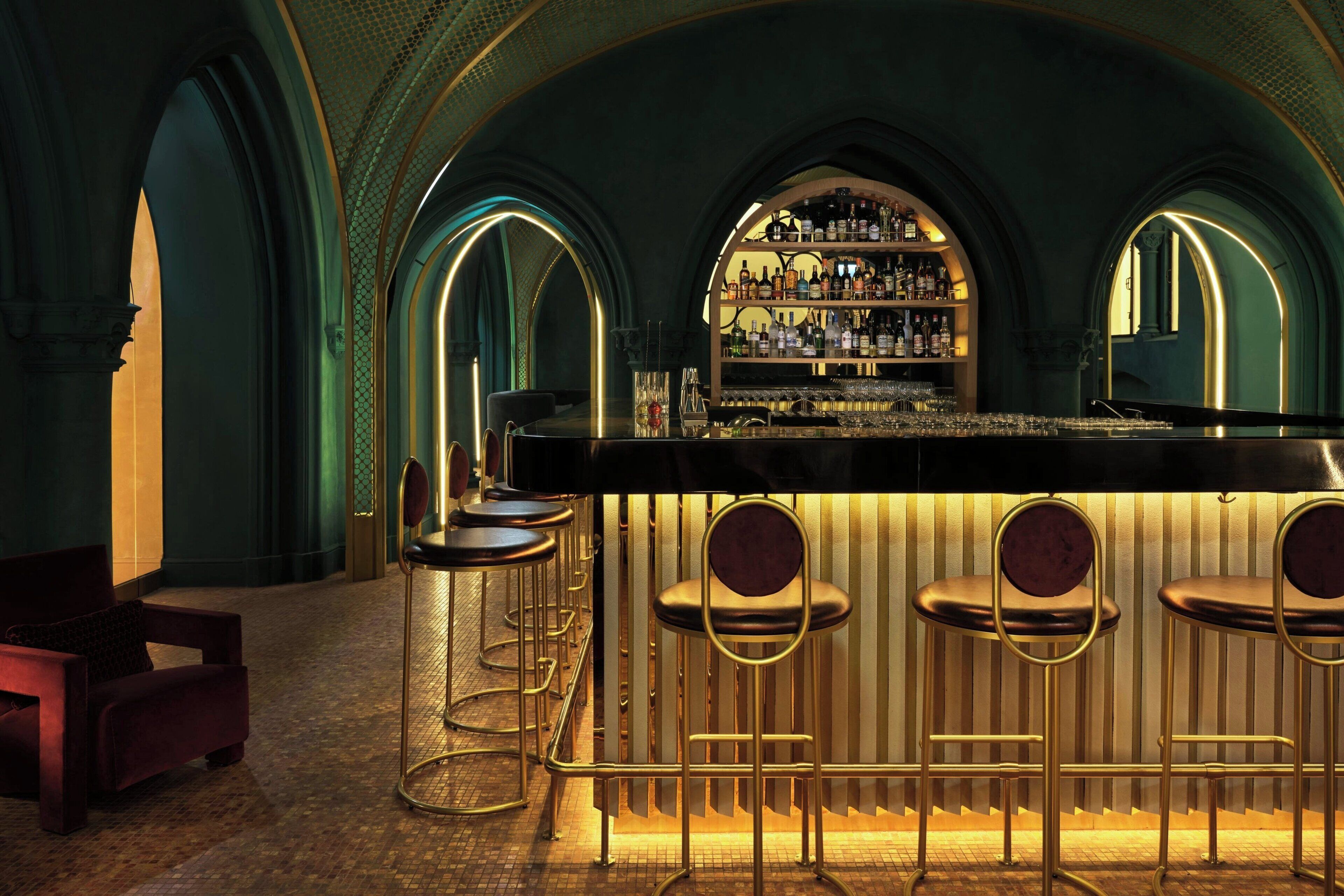 A bar area with a counter, stools, and a shelf of bottles.